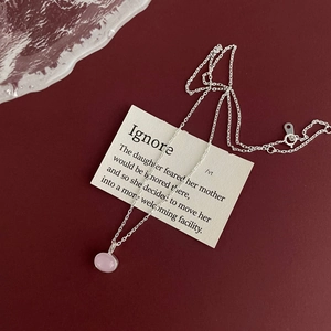 Detail of a minimalist silver necklace with a pink oval gemstone pendant and spring clasp