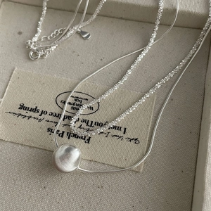 Vue macro d'un collier double rang en argent S925 avec perle brossée et chaîne serpent