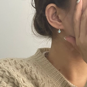 Close-up of S925 silver earring featuring a light blue moonstone on a female model