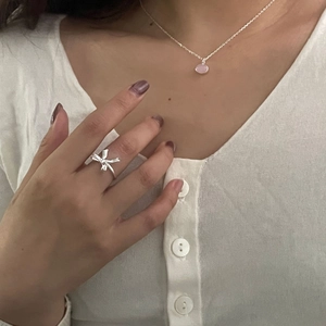 Detail view of 925 sterling silver bow ring and pink gemstone pendant worn by model