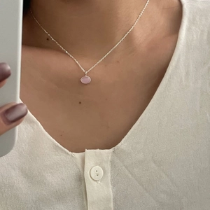 Detail of a minimalist 925 silver necklace with an oval pink gemstone on a delicate chain