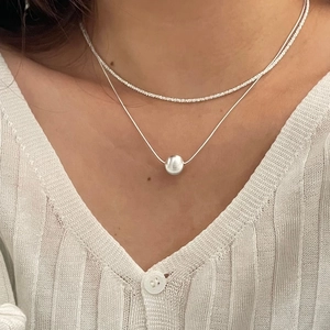 Détail d'un collier double rang en argent S925 avec une perle en métal poli sur maille serpent