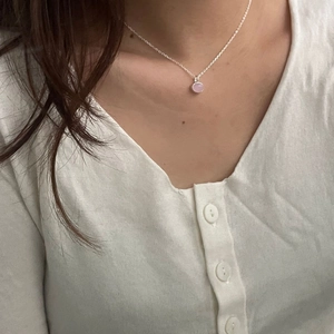Close-up of minimalist 925 silver necklace with a round pink gemstone on model