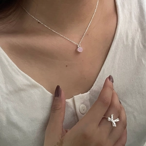 Detail of s925 silver necklace with pink gemstone and creative bow-shaped ring
