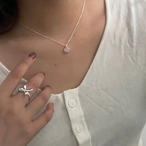 Detail of 925 sterling silver bow ring and pink pendant necklace worn by model