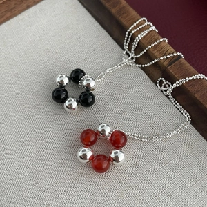 Detailed shot of silver beaded necklaces featuring black and red agate pendant charms