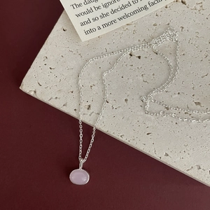 Detail of 925 sterling silver chain with a pink oval zircon pendant on a textured stone base