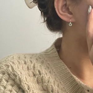 Close-up of S925 silver drop earring with aquamarine stone on a model wearing a beige sweater