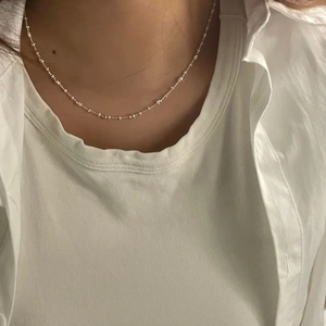 Detailed close-up of a silver S925 satellite bead chain necklace on a model neck