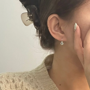 Close-up of a minimalist silver hoop earring with a sparkling round gemstone on a model