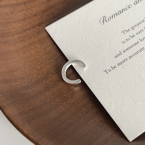 Minimalist S925 sterling silver ear cuff with polished C-shape design on wooden tray