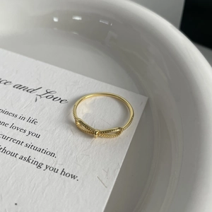 Elegant gold bow ring with textured band shown at 45-degree angle on aesthetic background