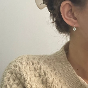 Close-up of S925 silver earring with round stone drop on model against a neutral background