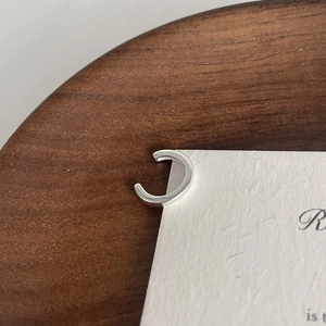 Close-up of minimalist S925 sterling silver ear cuff with polished silver finish