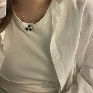 Detail of silver chain necklace with minimalist black and silver beaded ring pendant