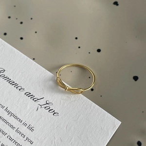 Close-up of fine S925 silver bow ring with textured beads on elegant card background