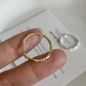 Detailed close-up of a gold oval bamboo-style open ring with elegant beaded metallic texture