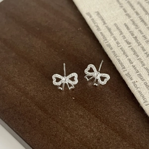 Détail de boucles d'oreilles nœud en argent S925 avec zircons sur fond de style vintage