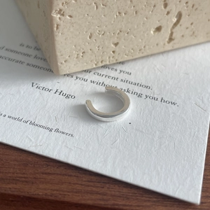 Minimalist S925 sterling silver ear cuff with polished finish on artistic paper