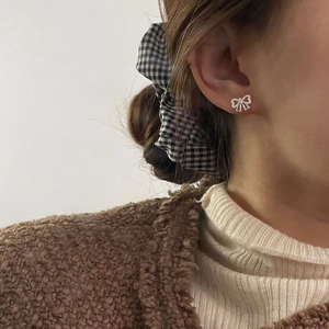 Boucles d'oreilles nœud en argent S925 avec zircons scintillants portées par un modèle