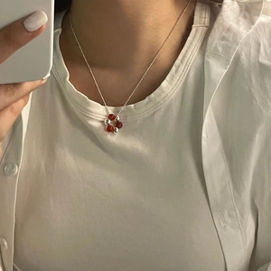 Detail view of S925 sterling silver chain with reddish-brown beads pendant on model
