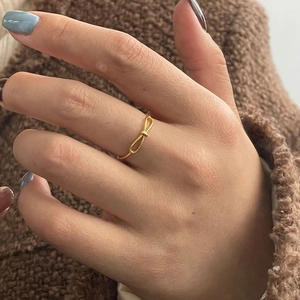 Detail of elegant gold twist knot ring worn on finger against textured background