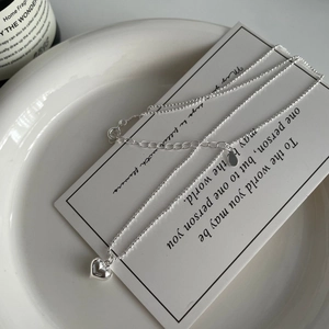 Vue détaillée d'un collier avec pendentif cœur en argent poli sur fond blanc épuré