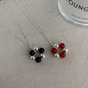 Detailed close-up of S925 sterling silver ball flower necklaces on grey linen background