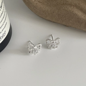 Détail de boucles d'oreilles nœud en argent avec zircone cubique sur socle en pierre
