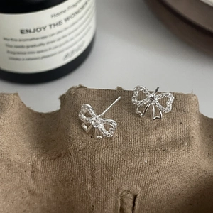 Vue macro de boucles d'oreilles nœud en argent avec zircons sur un fond rustique