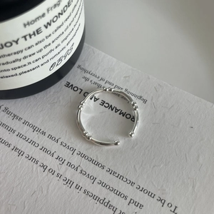 Detail shot of a minimalist silver bamboo joint open ring on a textured white paper background