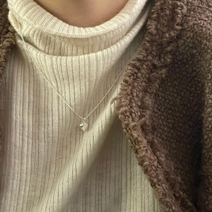 Gros plan d'un collier pendentif cœur minimaliste en argent sur un pull d'hiver
