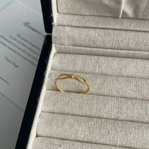 Minimalist gold bow-knot ring with bead texture shown on elegant cream jewelry box display