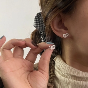Boucles d'oreilles nœud papillon en argent S925 avec zircone portées par le modèle