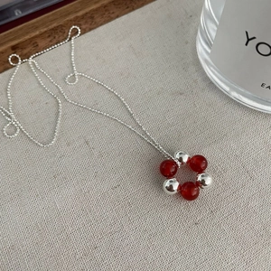 Macro detail of S925 silver necklace with red agate and silver bead circular pendant