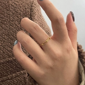 Close-up of golden bow knot ring with woven texture on a tweed background