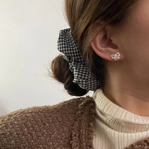 Gros plan de boucles d'oreilles nœud en argent S925 avec zircons portées par un mannequin