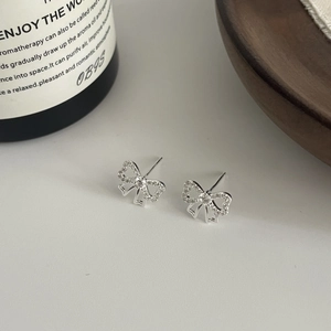 Détail de boucles d'oreilles nœud en argent avec zircons sur un fond minimaliste