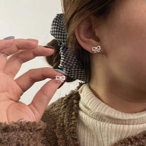 Détail des boucles d'oreilles nœud en argent S925 avec zircons portées avec élégance