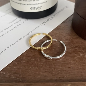 Detail of minimalist gold and silver open rings with small crystal on a wooden table