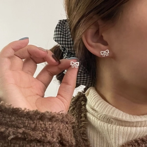 Gros plan de boucles d'oreilles nœud en argent S925 et oxydes de zirconium sur l'oreille