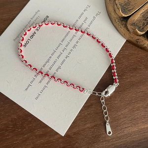 Close-up of S925 sterling silver beads and hand-woven red rope bracelet on a card
