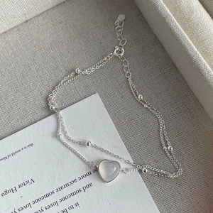 Gros plan du bracelet double rang en argent S925 avec pendentif cœur en calcédoine blanche