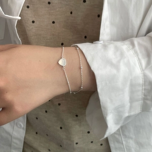 Gros plan d'un bracelet double rang en argent avec cœur en calcédoine blanche au poignet