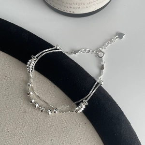 Détail d'un bracelet double épaisseur argenté avec perles et pendentif en cœur