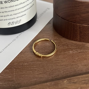 Detailed close-up of a minimalist golden fish open ring on a warm wooden surface