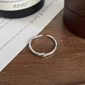 Macro shot of silver fish ring with a small zircon eye on a natural wood surface