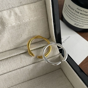 Gros plan de bagues minimalistes dorées et argentées mates dans un écrin de bijoux beige