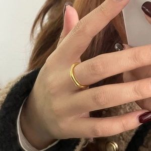 Gros plan d'une bague dorée ondulée minimaliste avec une texture mate élégante au doigt