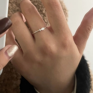 Macro shot of a minimalist S925 sterling silver ring featuring a small fish design on finger